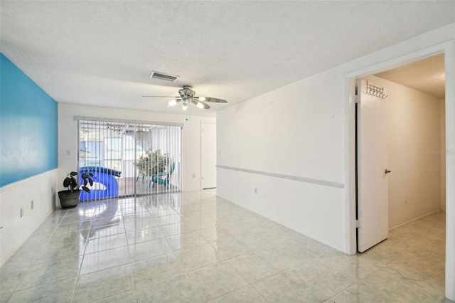 tiled empty room with a textured ceiling and ceiling fan