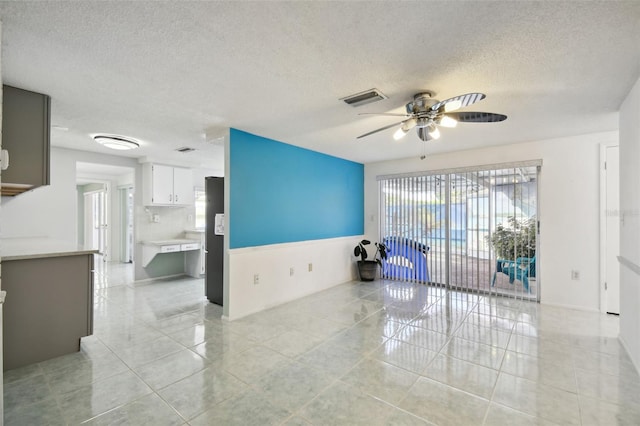 unfurnished room featuring a textured ceiling, light tile patterned floors, and ceiling fan