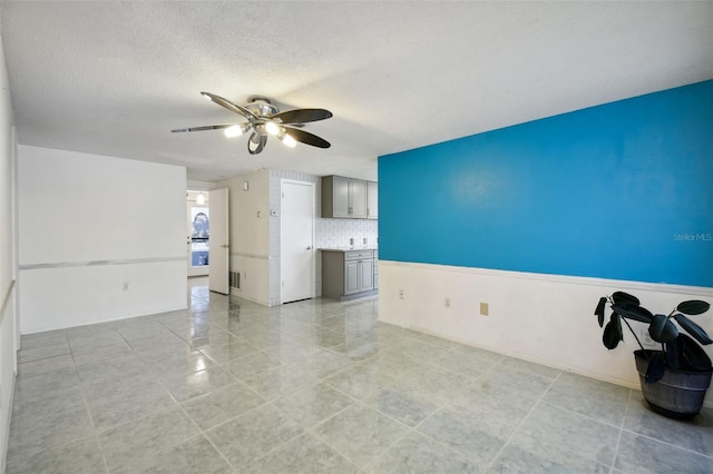 tiled empty room with ceiling fan and a textured ceiling