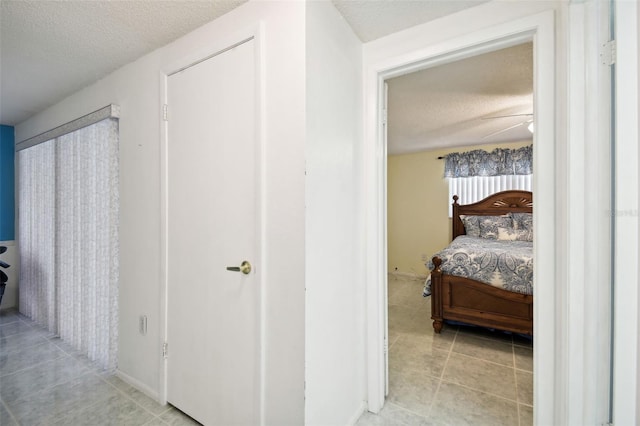 hall featuring a textured ceiling and light tile patterned floors