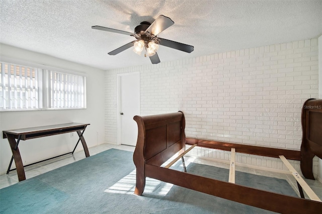 bedroom featuring brick wall, a textured ceiling, and ceiling fan