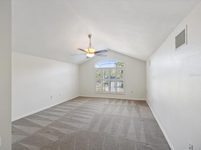 carpeted spare room featuring ceiling fan and vaulted ceiling