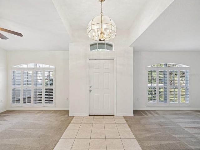 carpeted foyer entrance with ceiling fan with notable chandelier