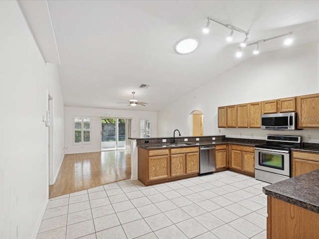 kitchen with sink, kitchen peninsula, light hardwood / wood-style floors, stainless steel appliances, and lofted ceiling