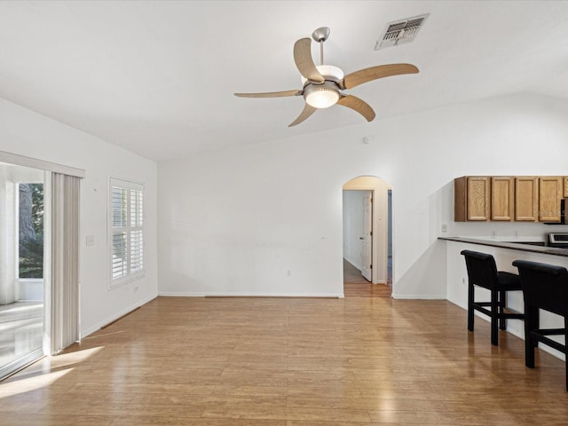 living room with ceiling fan, vaulted ceiling, and light wood-type flooring