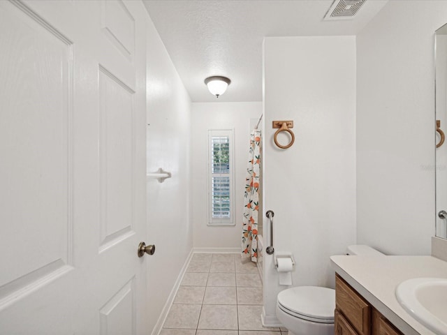 bathroom featuring vanity, toilet, tile patterned floors, and a textured ceiling