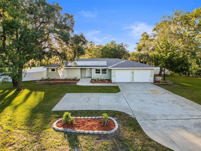 ranch-style home featuring solar panels, a garage, and a front lawn