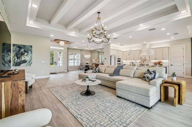 living room featuring beam ceiling, french doors, a notable chandelier, and light wood-type flooring