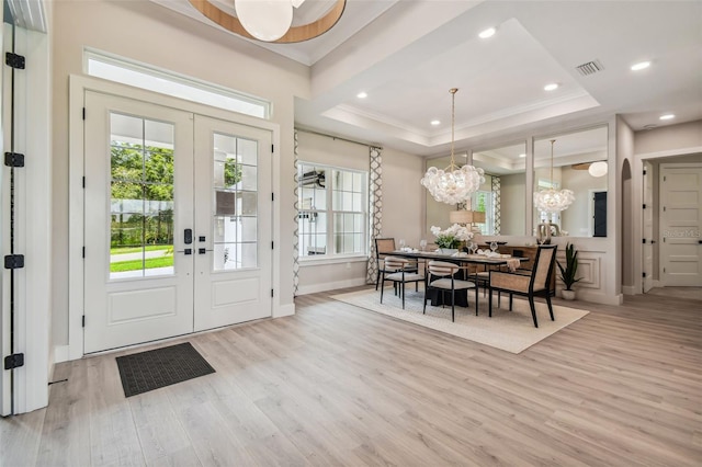 dining room featuring light hardwood / wood-style floors, french doors, and a tray ceiling