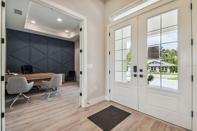 doorway to outside featuring light hardwood / wood-style floors, french doors, ornamental molding, and a tray ceiling