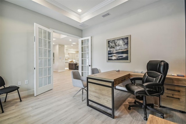 office space with ornamental molding, french doors, light wood-type flooring, and a raised ceiling