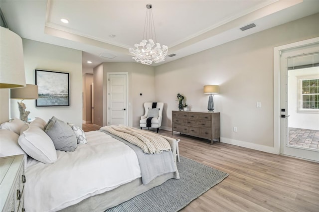 bedroom featuring ornamental molding, light hardwood / wood-style flooring, a notable chandelier, and a raised ceiling