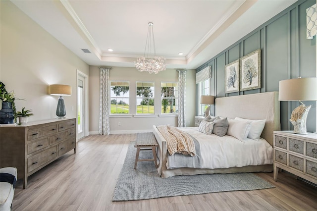 bedroom with crown molding, a chandelier, a tray ceiling, and light wood-type flooring