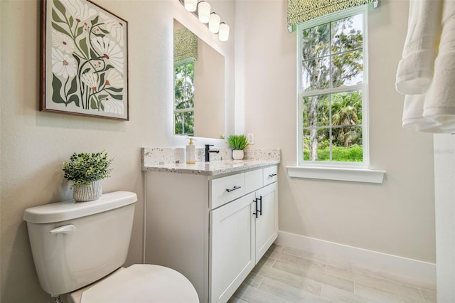 bathroom featuring toilet, hardwood / wood-style flooring, vanity, and plenty of natural light