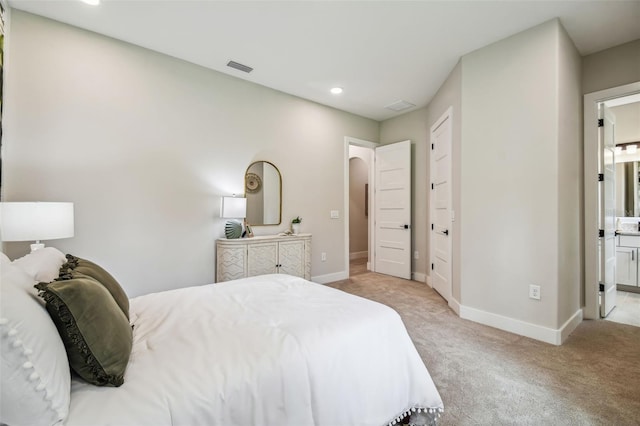 bedroom with connected bathroom and light colored carpet