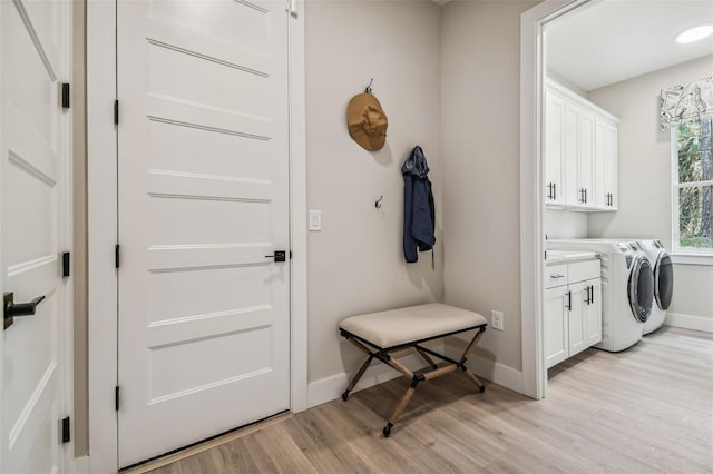 laundry room featuring light hardwood / wood-style flooring, cabinets, and separate washer and dryer