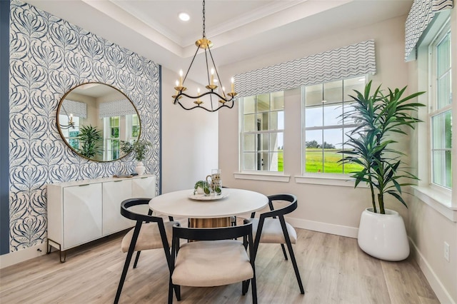 dining room featuring a notable chandelier, ornamental molding, a tray ceiling, and light wood-type flooring