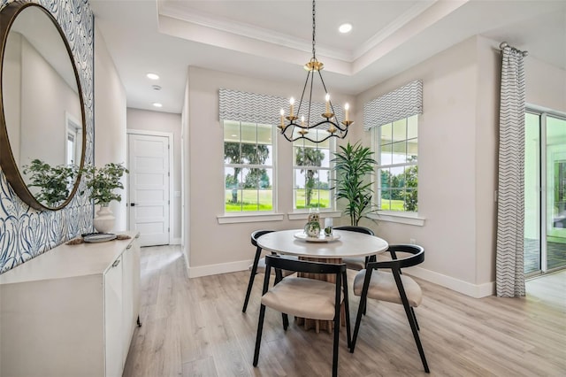 dining room with a notable chandelier, a tray ceiling, ornamental molding, and light hardwood / wood-style flooring