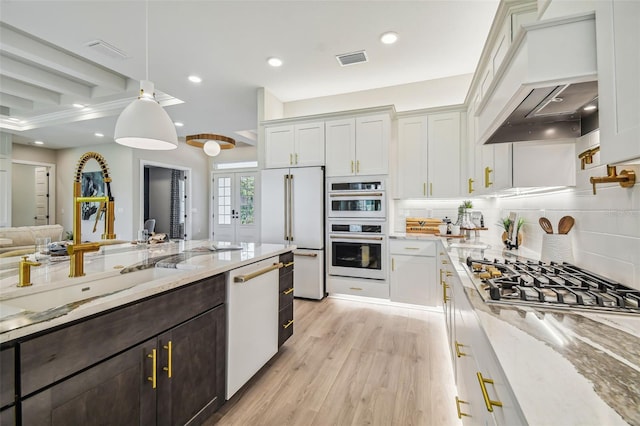 kitchen with white cabinets, light stone counters, light hardwood / wood-style flooring, decorative light fixtures, and stainless steel appliances