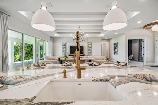 kitchen with crown molding, light stone counters, pendant lighting, and a tray ceiling