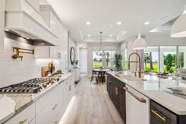 kitchen featuring white cabinetry, a healthy amount of sunlight, decorative light fixtures, and custom exhaust hood