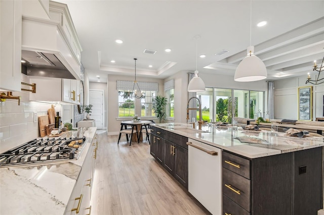 kitchen featuring a spacious island, a raised ceiling, white cabinetry, and decorative light fixtures