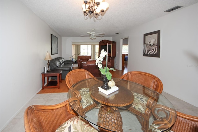 dining room featuring a textured ceiling, ceiling fan with notable chandelier, and light tile patterned floors