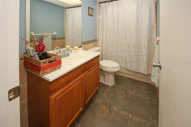 full bathroom with vanity, toilet, tile walls, and shower / tub combo