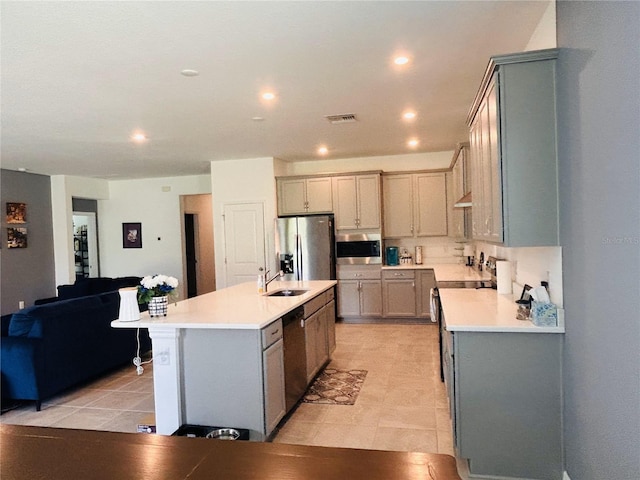 kitchen featuring stainless steel appliances, sink, gray cabinets, and a kitchen island with sink