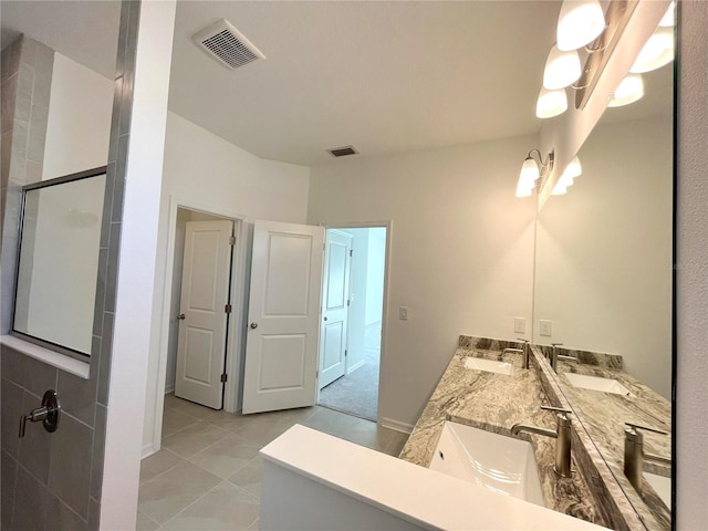 bathroom with a shower with door, vanity, and tile patterned flooring