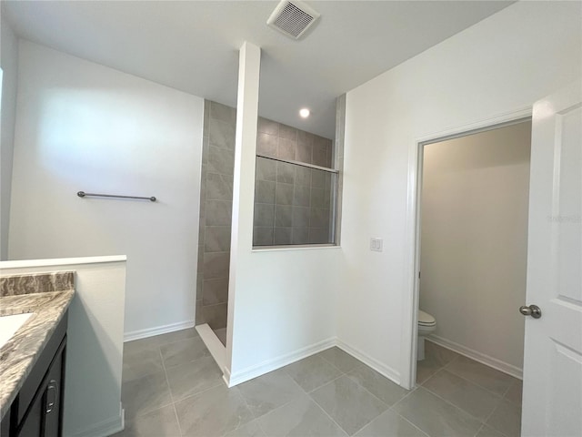 bathroom with vanity, toilet, and tiled shower