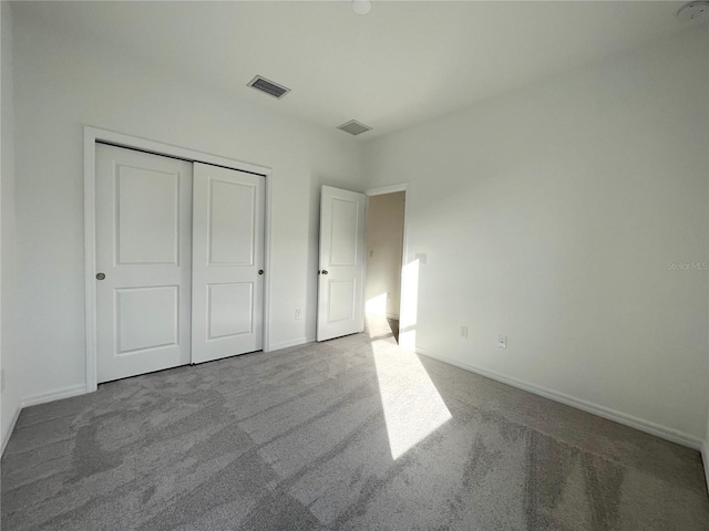 unfurnished bedroom with a closet and light colored carpet