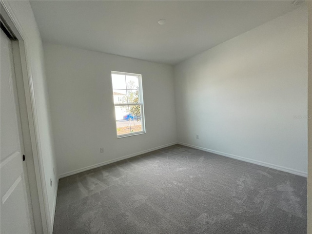 carpeted spare room featuring baseboards