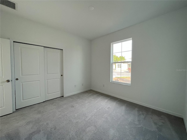 unfurnished bedroom with a closet and light colored carpet