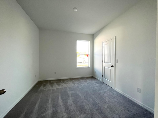 unfurnished room featuring dark colored carpet