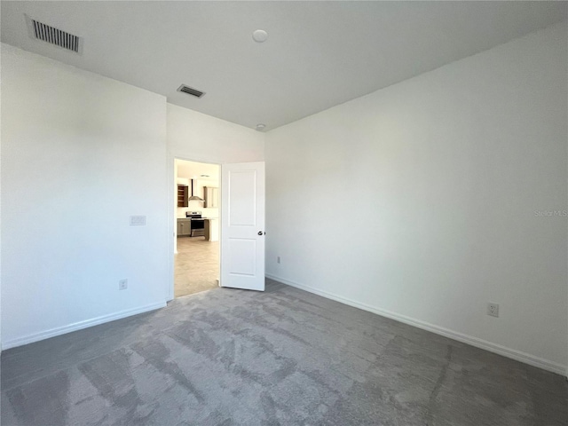 carpeted spare room featuring lofted ceiling