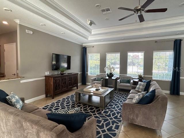 tiled living room featuring ornamental molding, ceiling fan, and a raised ceiling