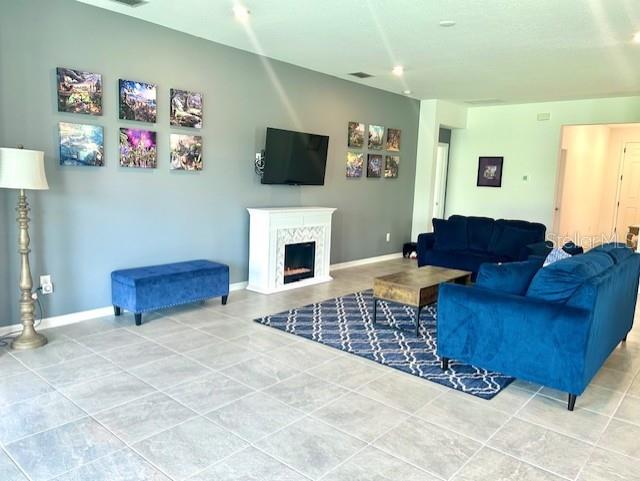 13447 Newport Shores Dr, Hudson, FL 34669 - tiled living area featuring a high end fireplace and baseboards
