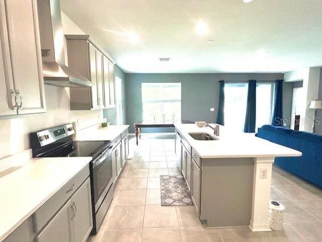 13447 Newport Shores Dr, Hudson, FL 34669 - kitchen with appliances with stainless steel finishes, wall chimney range hood, a center island with sink, light countertops, and gray cabinets