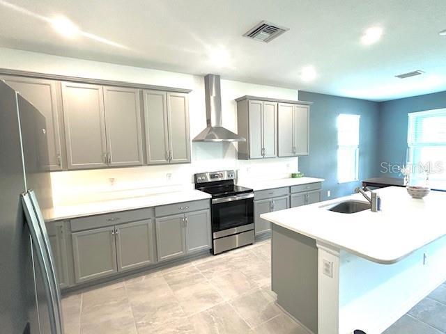 13447 Newport Shores Dr, Hudson, FL 34669 - kitchen featuring appliances with stainless steel finishes, wall chimney exhaust hood, gray cabinetry, and light countertops