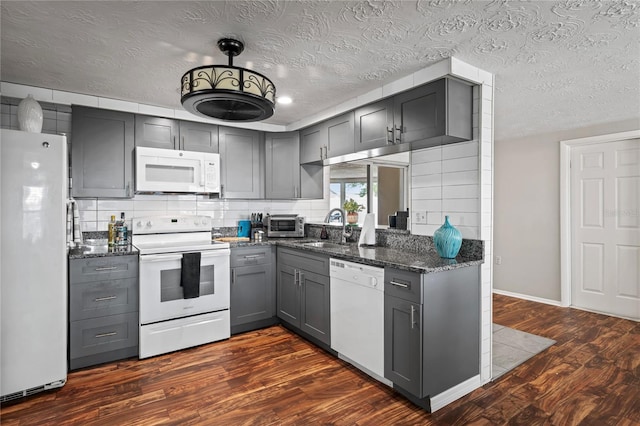 kitchen with dark hardwood / wood-style flooring, white appliances, a textured ceiling, dark stone countertops, and gray cabinets