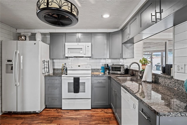 kitchen with a textured ceiling, gray cabinets, dark hardwood / wood-style flooring, and white appliances