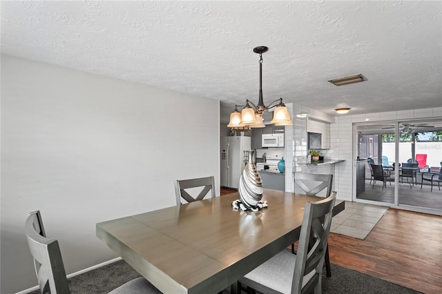 dining space with a textured ceiling and dark hardwood / wood-style floors