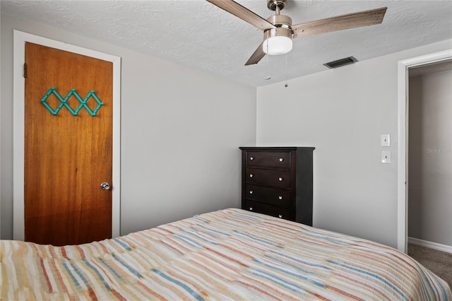 carpeted bedroom with ceiling fan and a textured ceiling