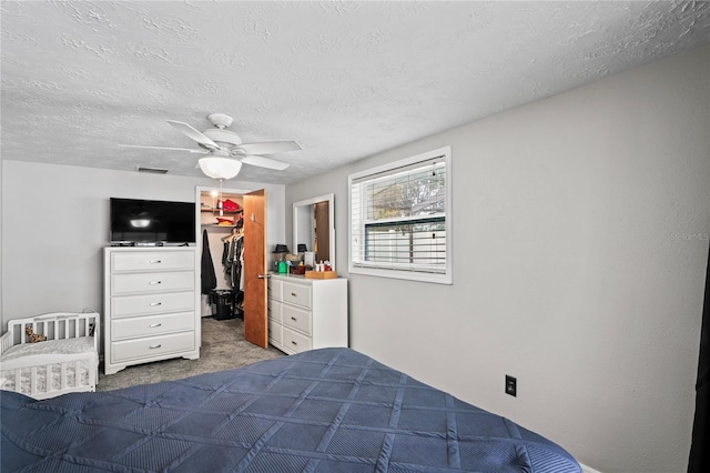 unfurnished bedroom featuring a walk in closet, ceiling fan, a closet, and a textured ceiling