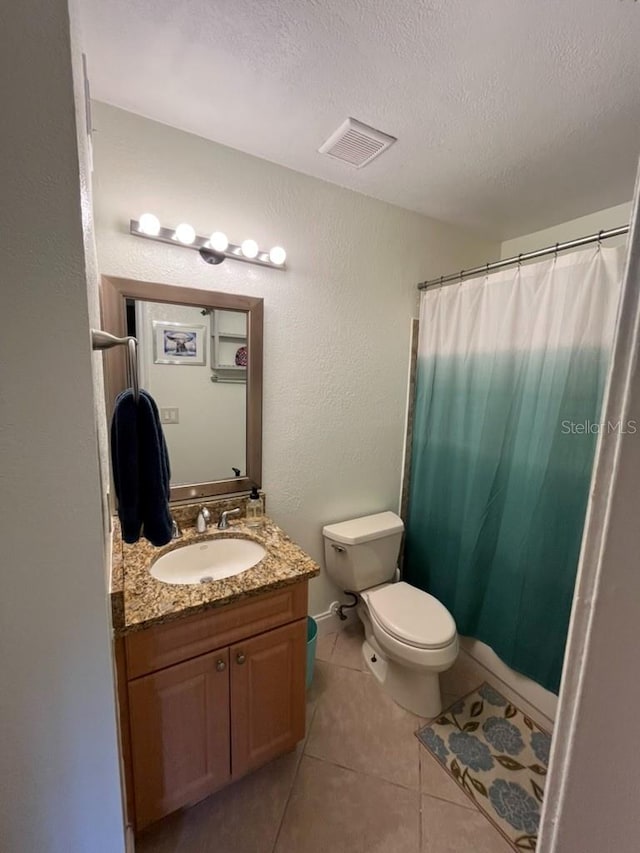 bathroom featuring curtained shower, a textured ceiling, toilet, tile patterned floors, and vanity