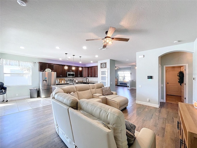 living room featuring light hardwood / wood-style flooring, a textured ceiling, and ceiling fan