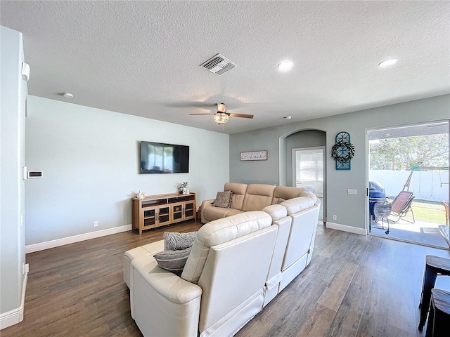 living room with a textured ceiling, dark hardwood / wood-style floors, and ceiling fan