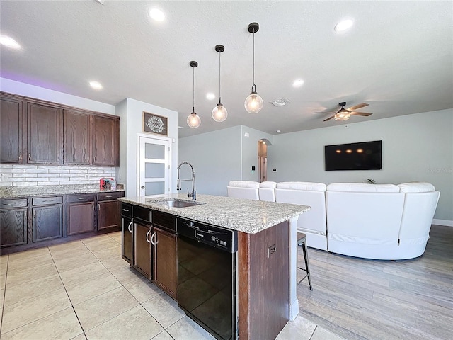 kitchen featuring sink, dishwasher, pendant lighting, a breakfast bar area, and a kitchen island with sink