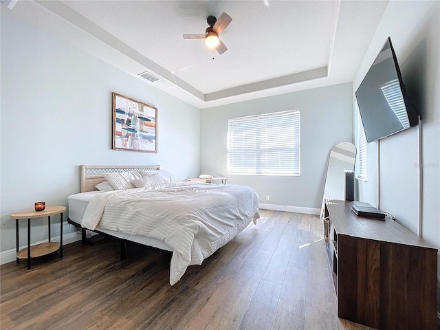 bedroom featuring hardwood / wood-style floors, a raised ceiling, and ceiling fan